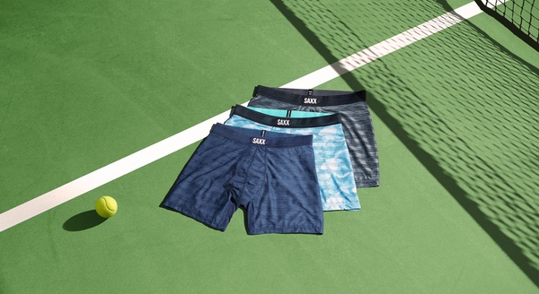 Three pairs of DropTemp Cooling Mesh Boxer Briefs lying flat overlapping one another next to a tennis ball on a sport court