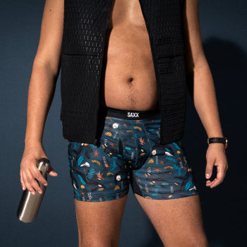Man in patterned boxer briefs and black vest holding water bottle