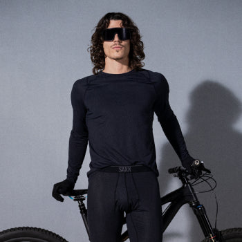 Man standing in front of a bike while wearing black baselayer top and tights