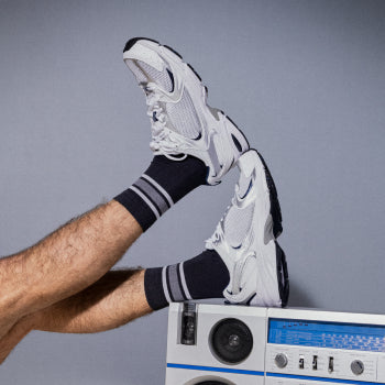 Man in white sneakers and blue socks with feet on boombox
