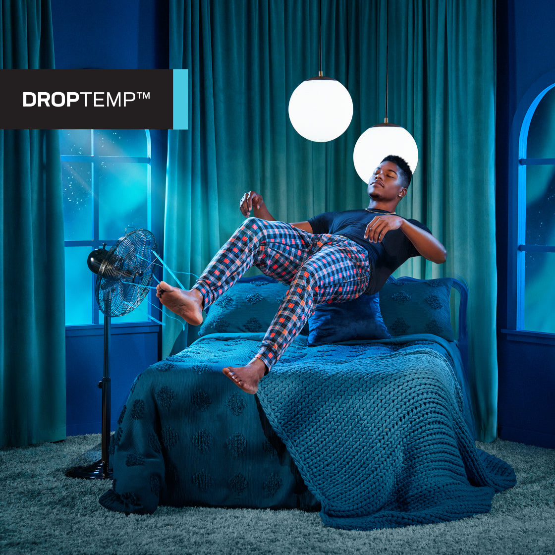 Man in pajamas and black shirt floating above bed with eyes closed