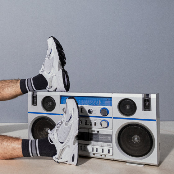 Man in white sneakers and blue socks with feet on boombox