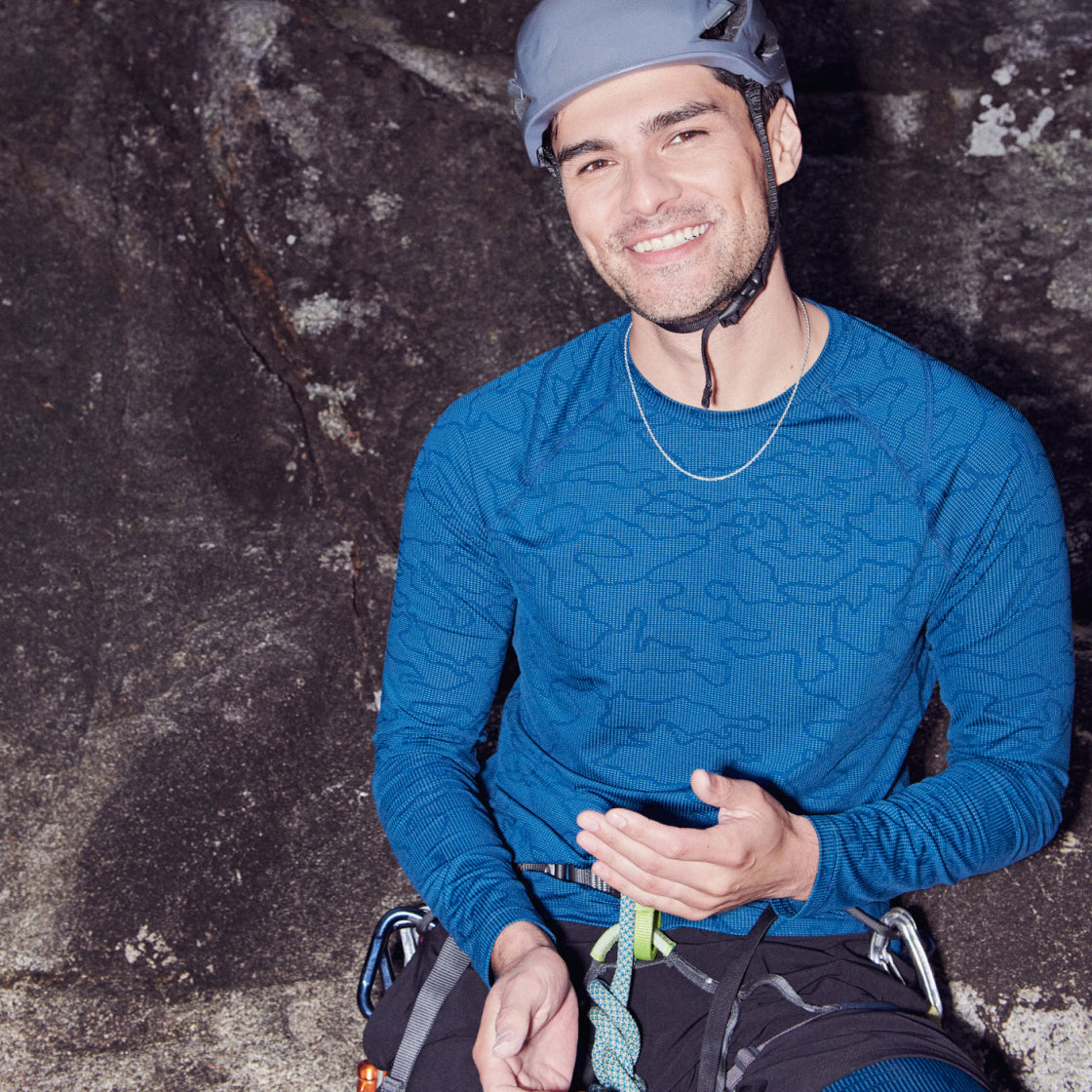 Rock climber wearing blue baselayer top and a gray helmet