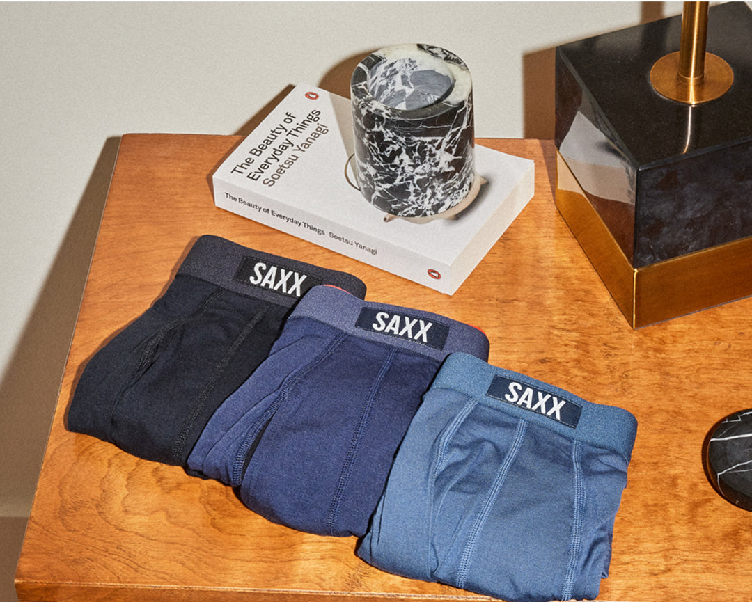 Three pairs of Saxx Underwear folded neatly on a wooden table