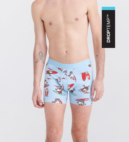 Man wearing light blue boxer briefs in surfing santa print