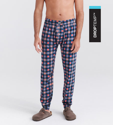 Man wearing cooling sleep pants in a plaid pattern and beige slippers