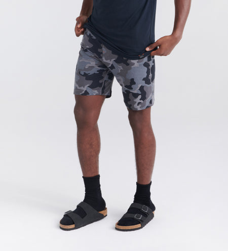 Man wearing black sleep shorts in a camoflague print and black sandals