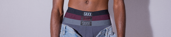Shirtless man in jeans with button undone showing multiple pairs of underwear
