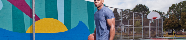 Man in striped shirt holding basketball on court