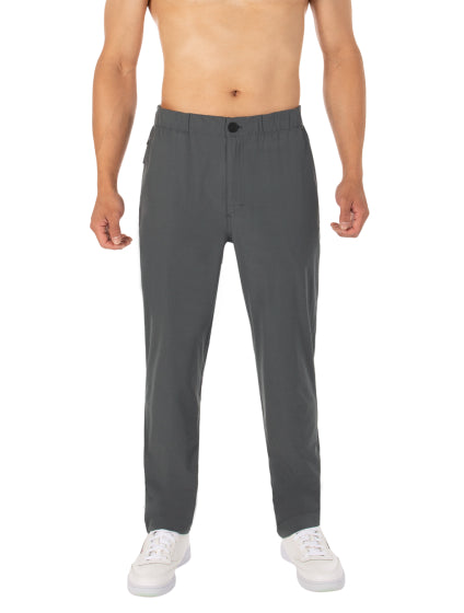 A photo of a man’s legs and feet from below the chest. He is wearing a pair of pants and running shoes.