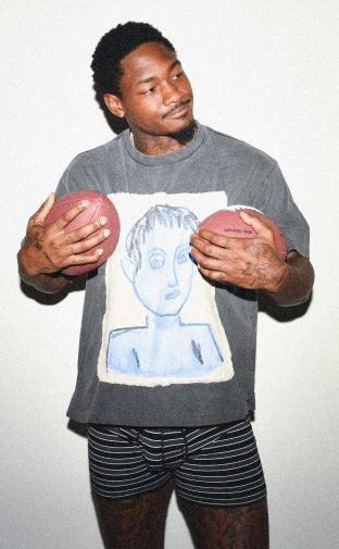 Stefon Diggs holding two footballs to his chest while wearing the Ultra Super Soft Boxer Brief in Black Crew Stripe