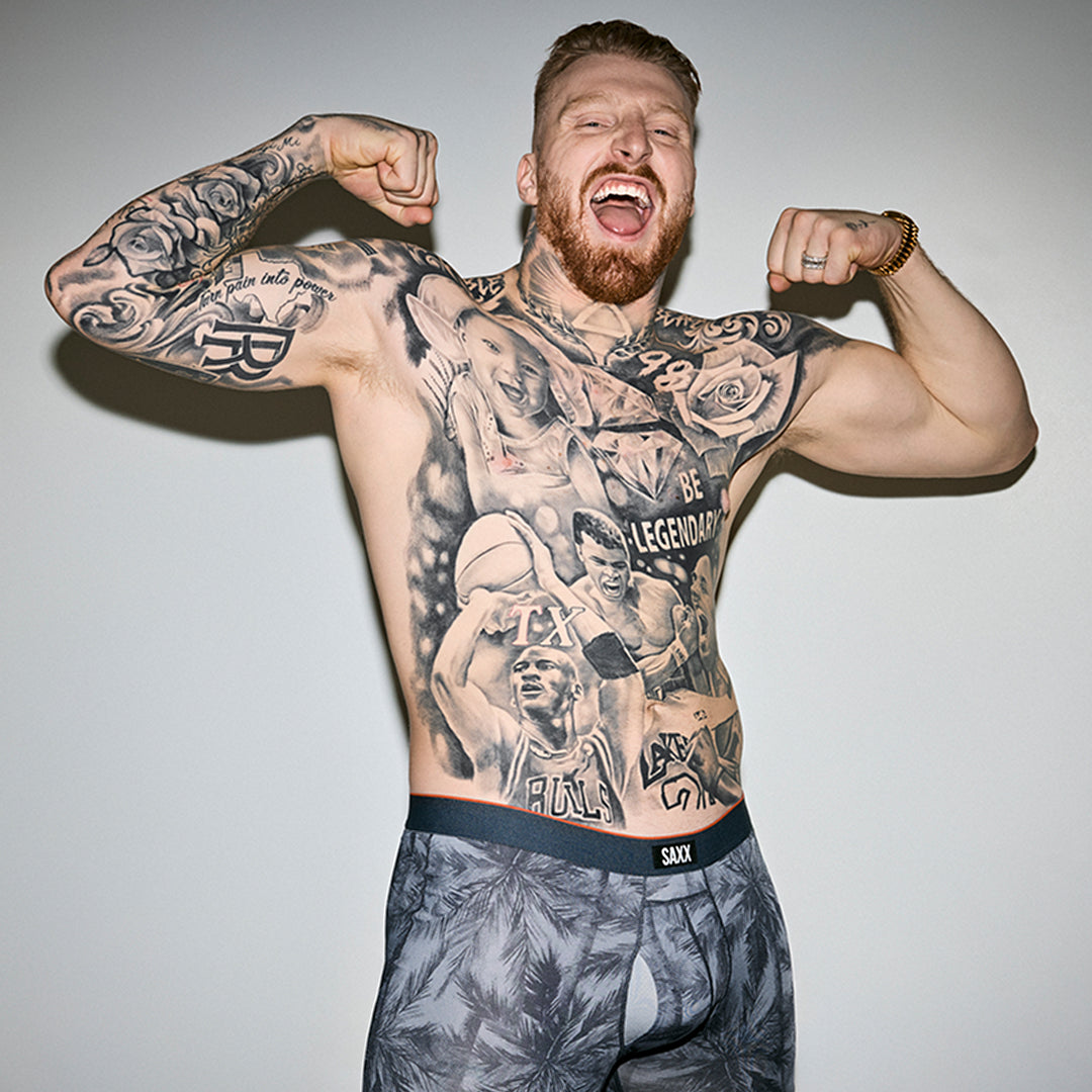 SAXX Gamechanger and Pro Football player Max Crosby flexes his arms while wearing only the Multi-Sport Mesh Boxer Brief