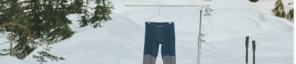 Baselayer hanging from pole in winter environment beside ski poles