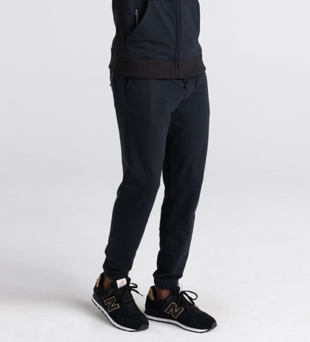 Man wearing black sweat pants and zip up hoodie with black sneakers