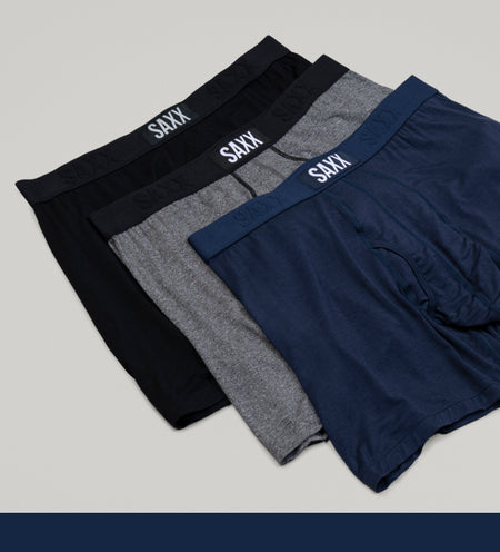 Three boxer briefs in black, grey, and blue arranged on top of one another