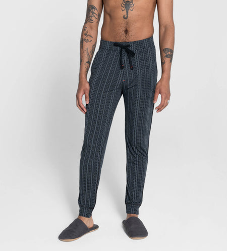 Shirtless man standing in striped sleep pants and slippers