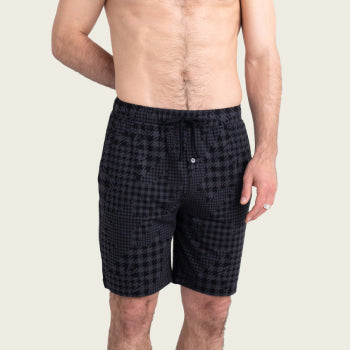 Shirtless man in black checkered shorts with hand behind back