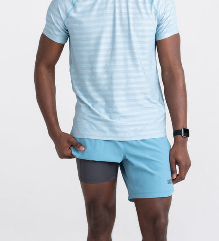 Man in blue shorts and shirt lifting leg to show liner