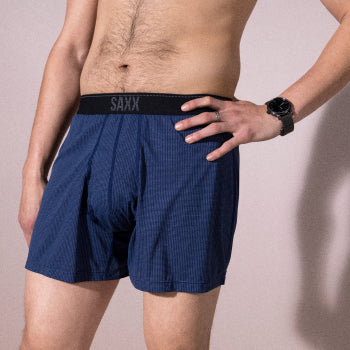 Shirtless man in blue boxer shorts standing with hand on hip