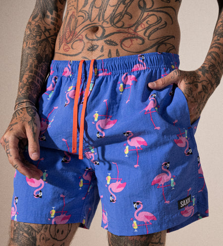 Tattooed man wearing blue shorts in a flamingo print