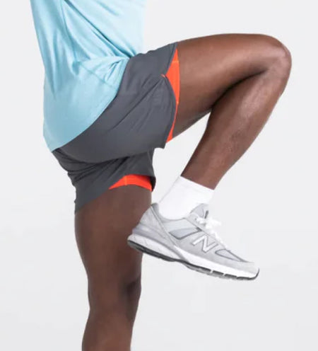 Man doing knee highs in gray shorts with an orange liner