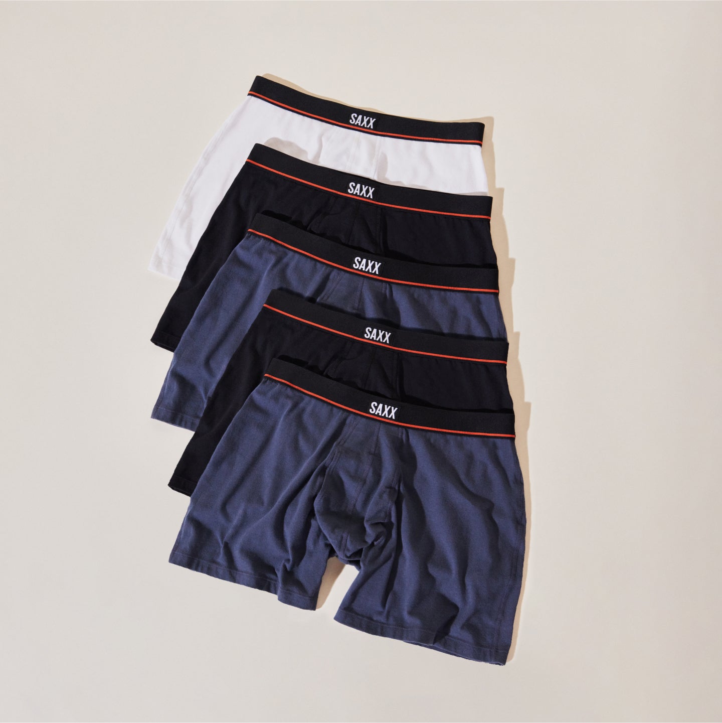 Five pairs of SAXX Boxer Briefs in White, Black and Navy stacked on top of each other