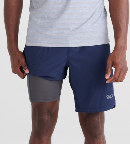 Man wearing navy blue 2N1 Shorts while lifting the leg to reveal liner