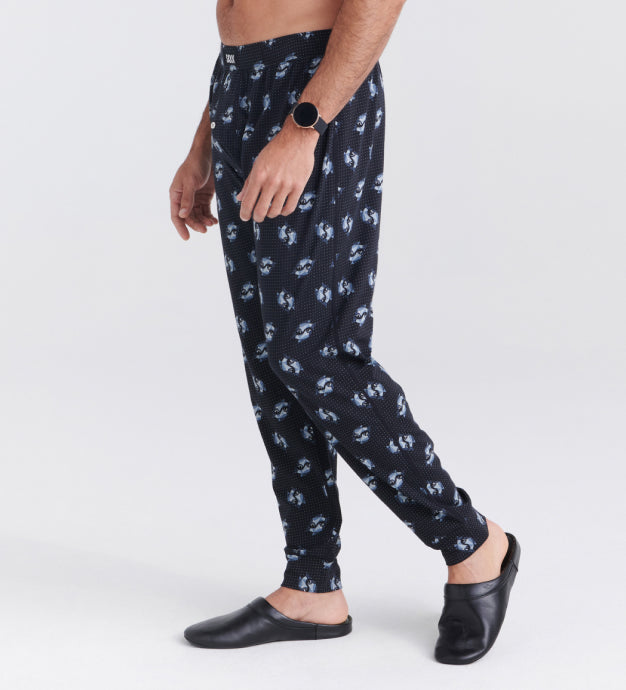 Man wearing black cooling Sleep Pants in shark print and black leather slippers