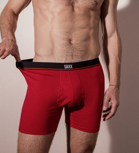 Man wearing red Boxer Briefs while stretching the waistband with his thumb