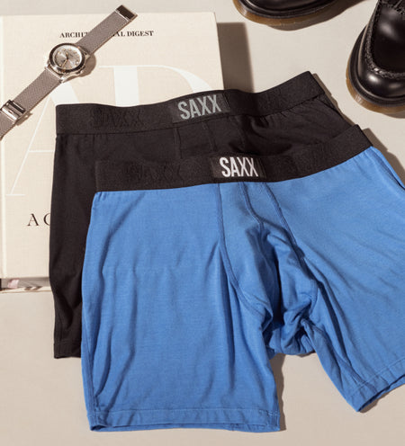 Two pairs of Boxer Briefs in blue and black placed over a magazine