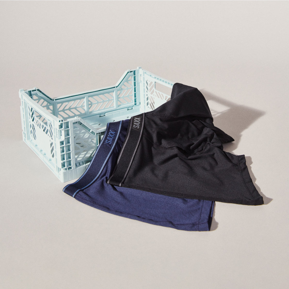 Two pairs of SAXX boxer briefs laid out over the edge of a milk crate on a white backdrop.