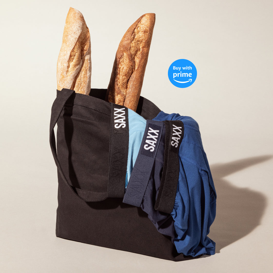 A black cloth bag holding two baguettes and three pairs of boxer briefs in different shades of blue