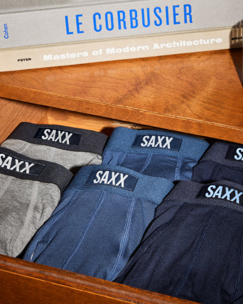 SAXX underwear in various colors on a wooden surface with books in the background