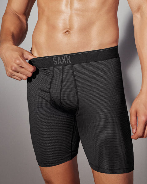 Man wearing black SAXX underwear against a gray background