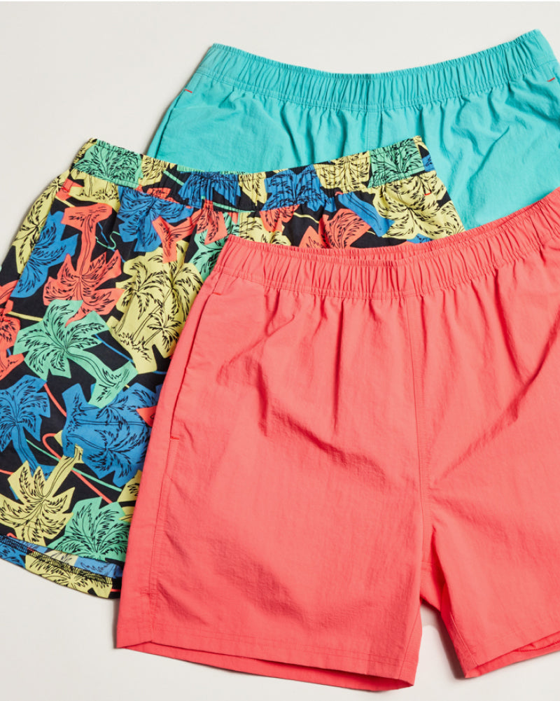 Three pairs of swim short laid on an off-white background.  