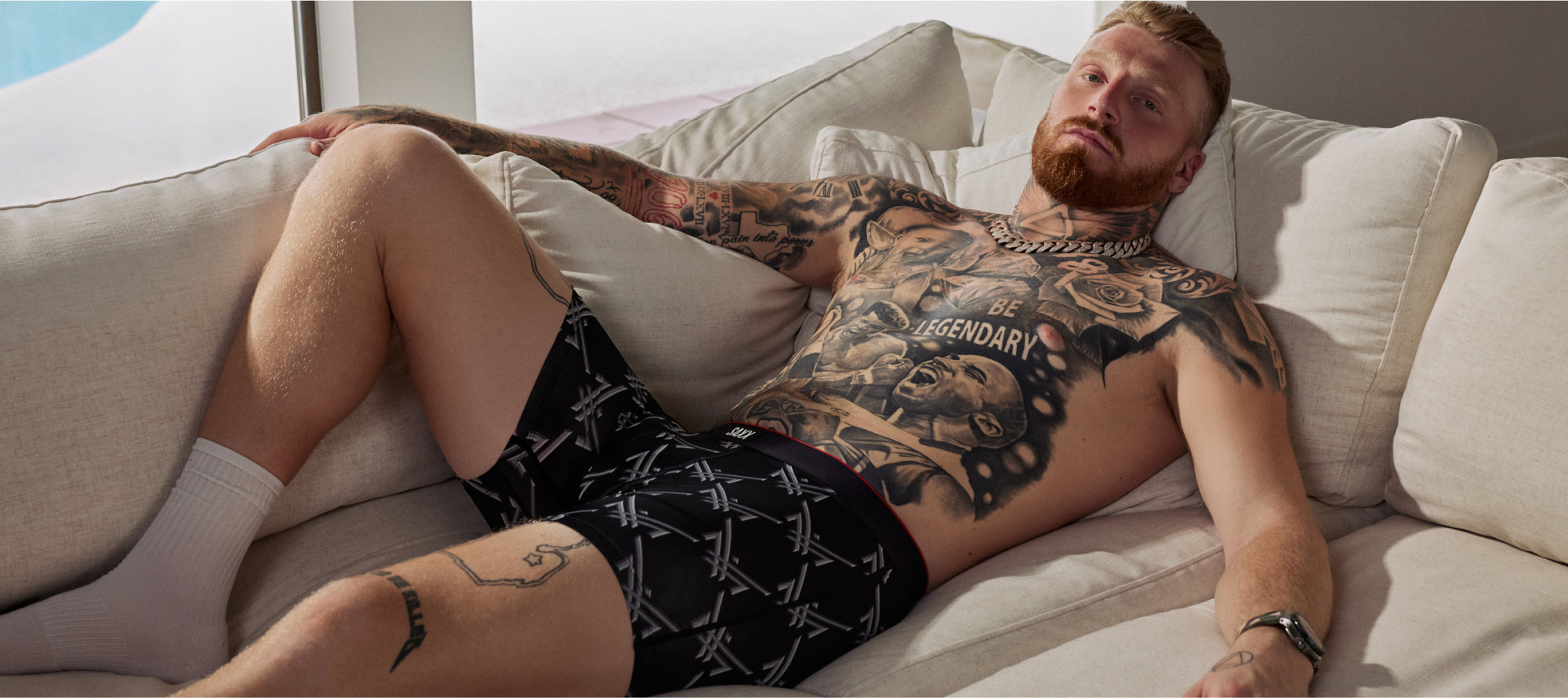 Maxx Crosby lying on a couch wearing black boxer briefs.