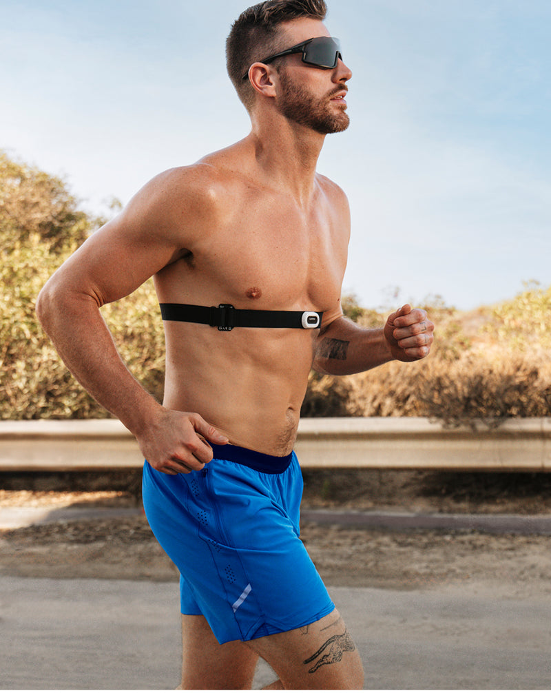 Man running outdoors wearing a heart rate monitor on his chest.