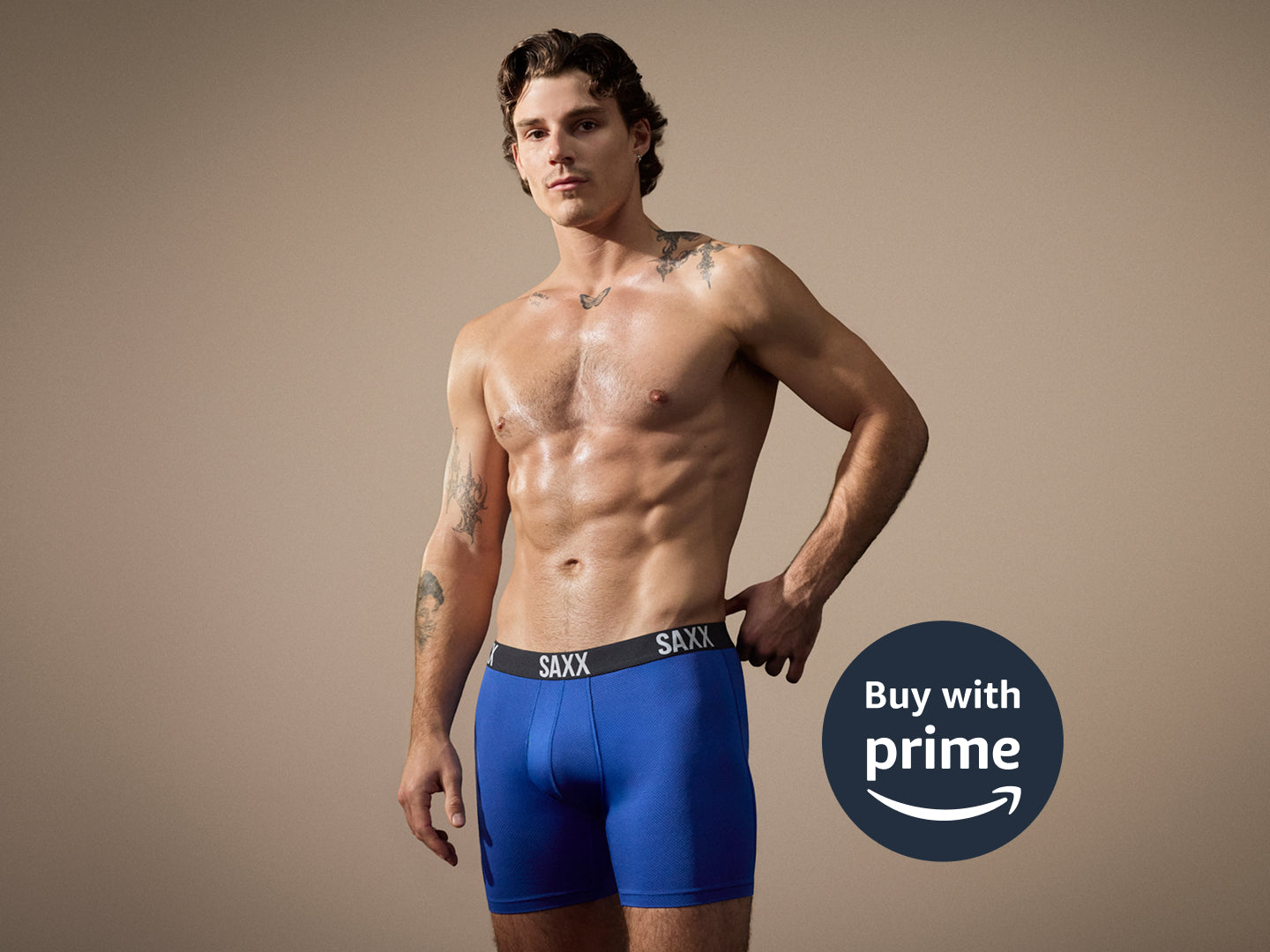 Man wearing blue boxer briefs with 'Buy with Prime' logo on a beige background