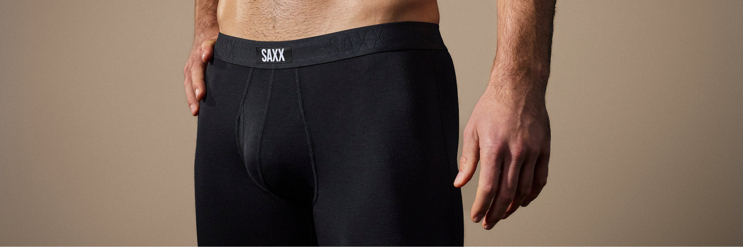 Black boxer briefs with 'SAXX' branding on a beige background