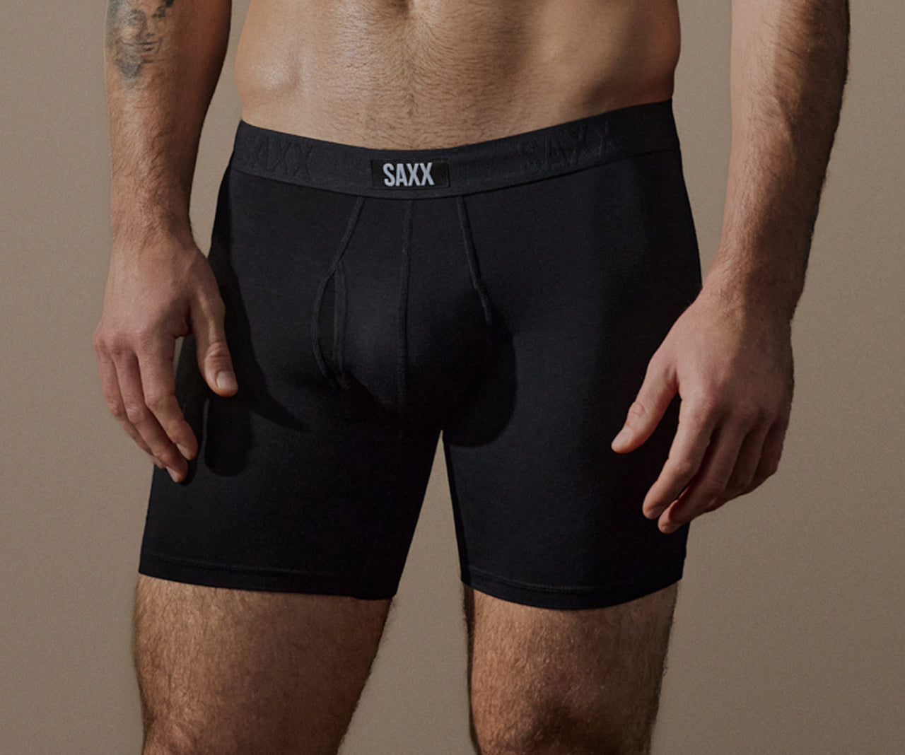 Person wearing black SAXX underwear on a beige background
