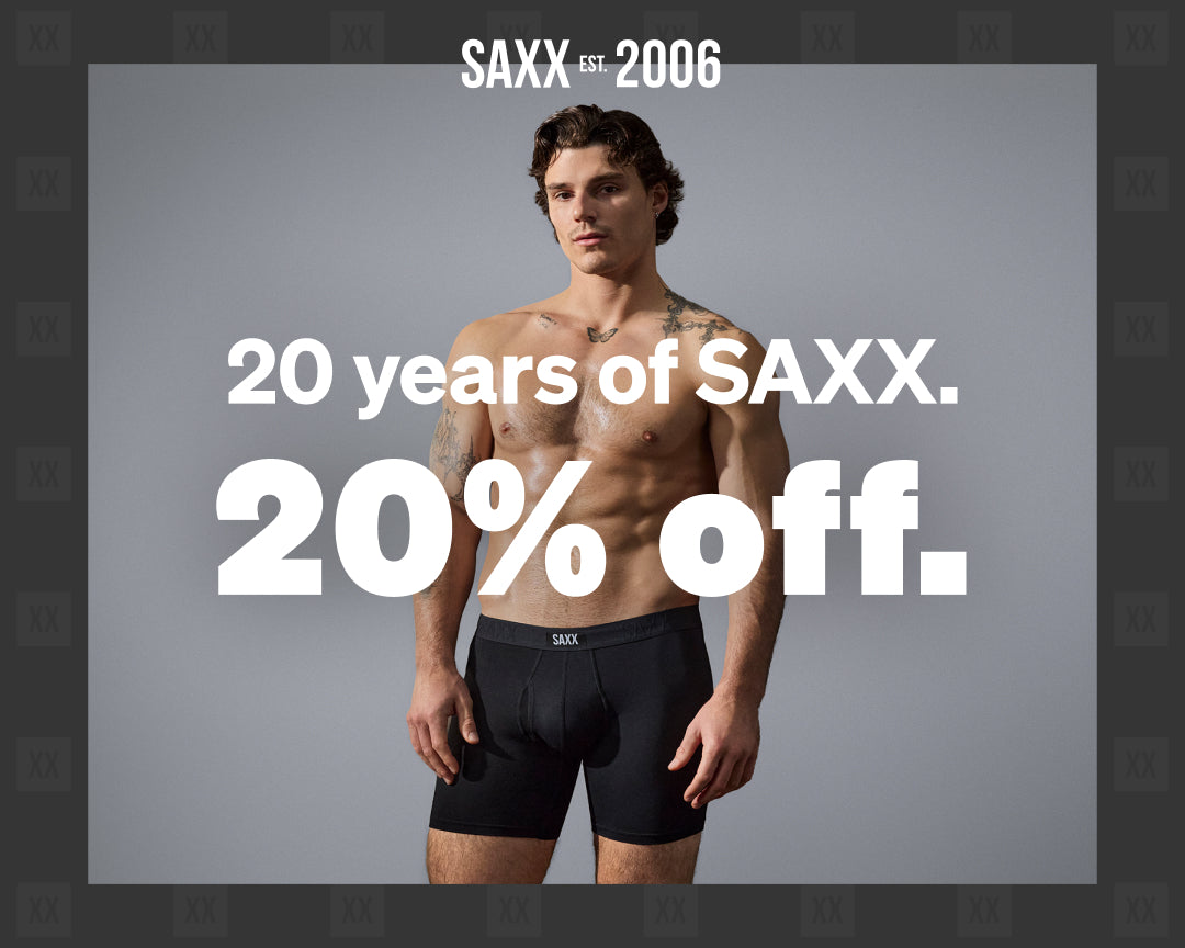 A promotional advertisement featuring a male model wearing black SAXX boxer briefs against a gray studio background, with large white text reading '20 years of SAXX. 20% off.