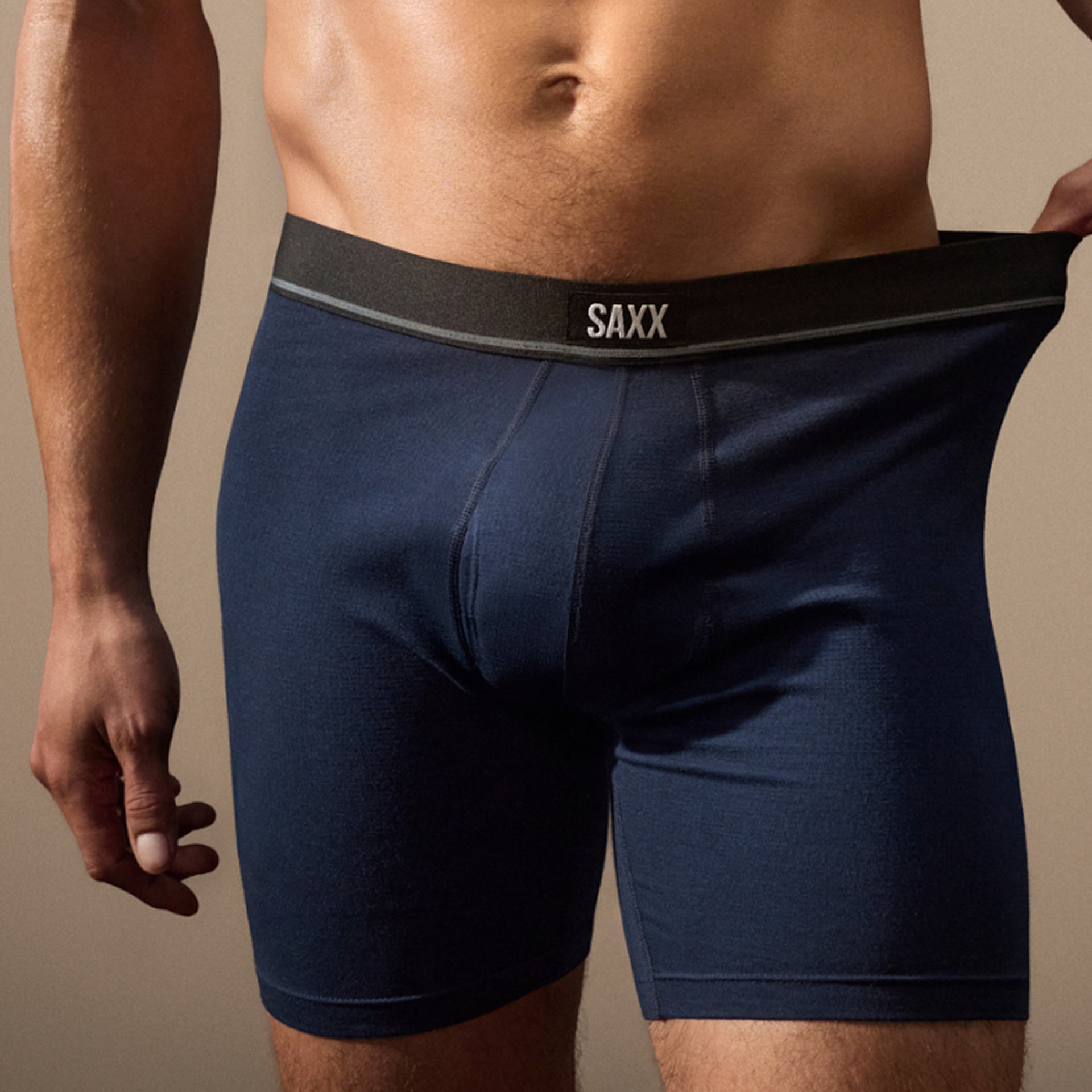 Navy blue boxer briefs with 'SAXX' branding on a beige background