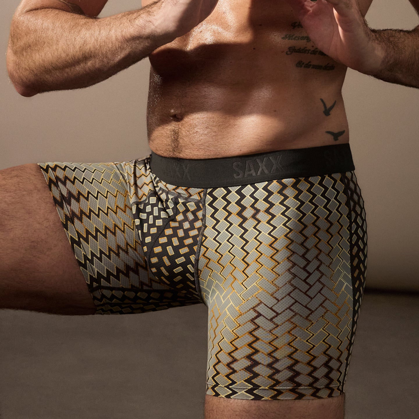 Man wearing patterned underwear with 'SAXX' brand visible on a neutral background