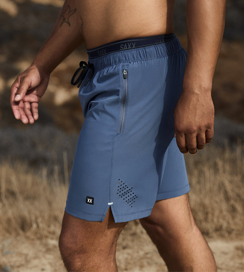 Man wearing blue athletic shorts with a blurred natural background