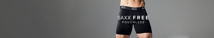 A model wearing black SAXX FREE POUCHLESS boxer briefs against a solid gray studio background.