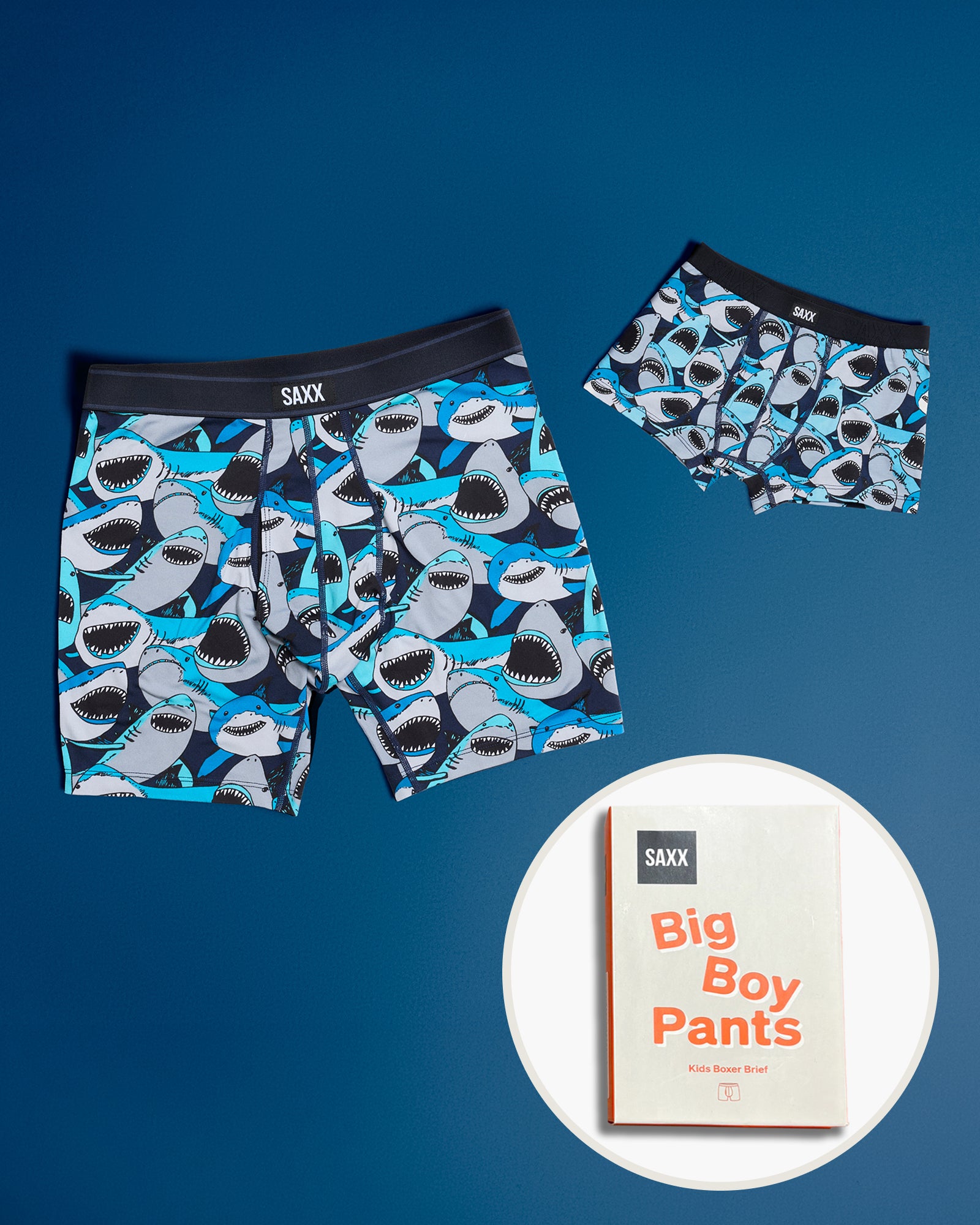 Matching men’s boxer brief and boys boxer brief featuring a blue shark print, shown with SAXX Big Boy Pants kids underwear packaging.