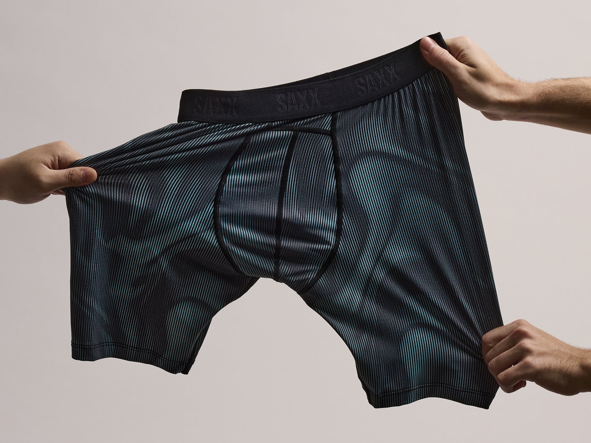 SAXX Underwear Smooth Flex boxer brief being stretched by hands in multiple directions.