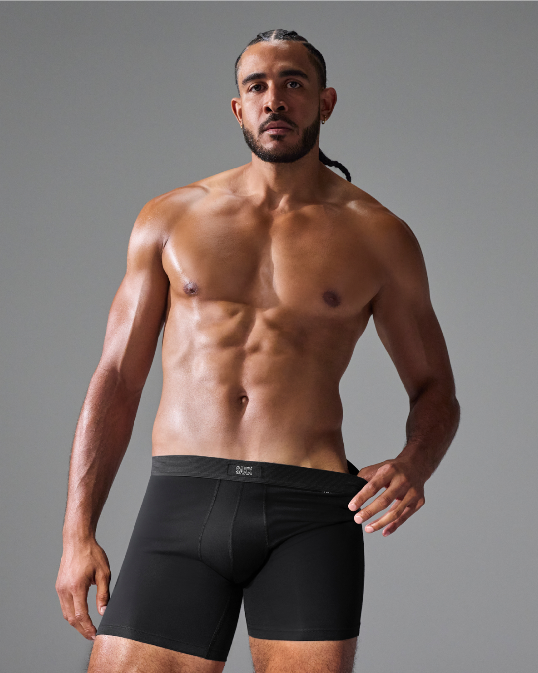 A shirtless male model wearing black boxer briefs, photographed against a plain gray studio background. The underwear has a visible G-1000 brand label at the front waistband.