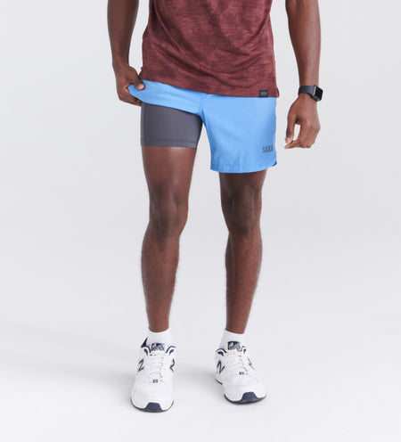 Man wearing blue performance shorts with a liner and white running shoes