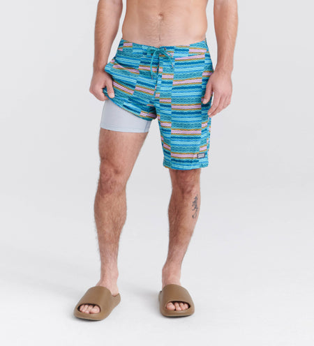 Man wearing striped blue swim shorts and brown sandals